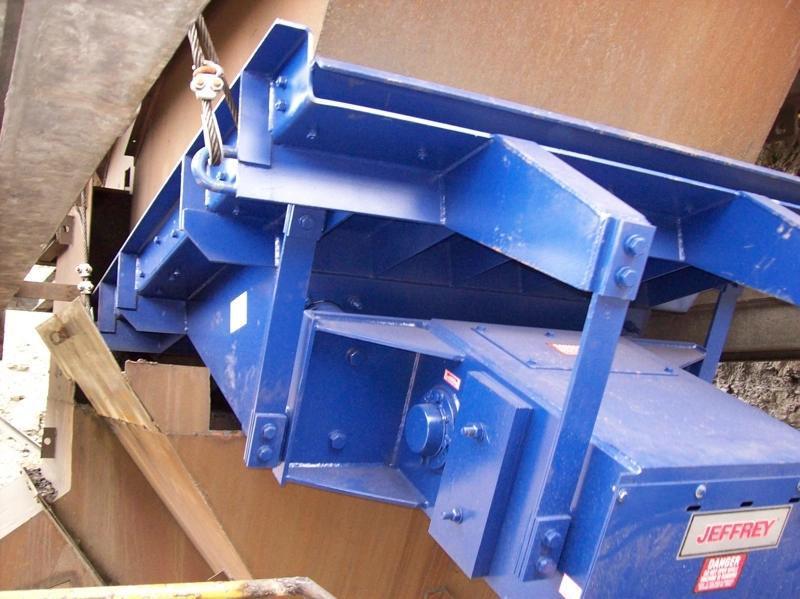 Jeffrey Rader® electromagnetic vibrating feeder installed beneath a material hopper, featuring a heavy-duty support frame and vibratory drive assembly for controlled bulk material handling.