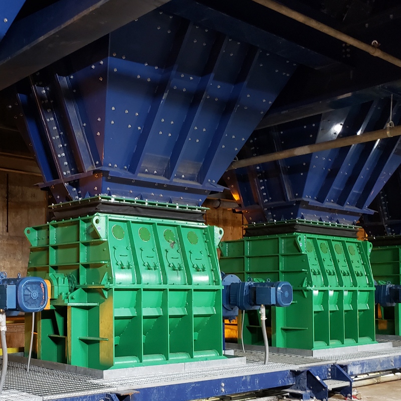 Multiple Pennsylvania Crusher POSIFLOW™ feeders installed beneath large storage hoppers in an industrial bulk material handling facility.