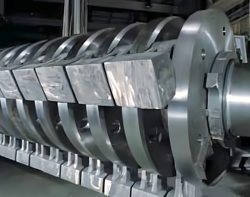 Close-up of Pennsylvania Crusher reversible impactor rotor with heavy-duty hammers mounted on shaft